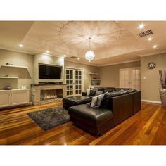 a large living room with wood floors and a fireplace in the center is lit by recessed lighting