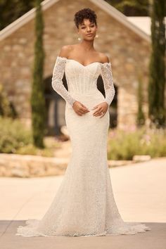 a woman in an off the shoulder wedding dress posing for a photo with her hands on her hips