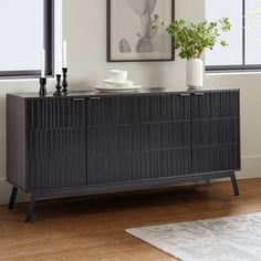 a black sideboard with two vases and a plant on it in front of a window