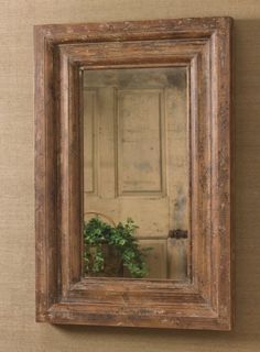 a mirror hanging on the wall above a potted plant in front of a door