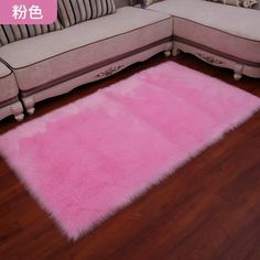 a pink area rug sitting on top of a wooden floor next to a white couch