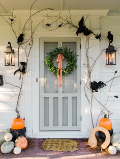 a front door decorated for halloween with pumpkins and decorations on the outside, and bats hanging from branches