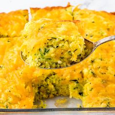 a close up of a casserole with broccoli and cheese on a spoon