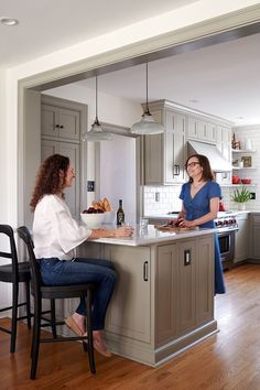 two women sitting at a kitchen counter talking