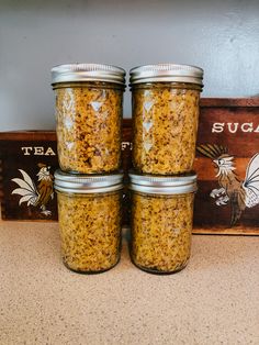 three jars filled with food sitting on top of a counter next to a wooden sign