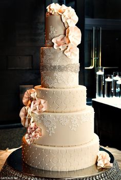 a three tiered wedding cake with pink flowers on the top and bottom, sitting on a table