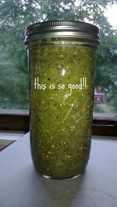 a jar filled with green stuff sitting on top of a counter next to a window