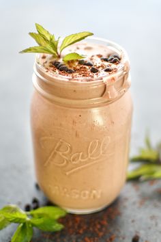 a mason jar filled with chocolate pudding and topped with a sprig of mint