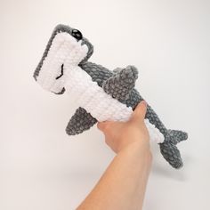 a hand holding a crocheted stuffed animal in it's right hand and the other arm