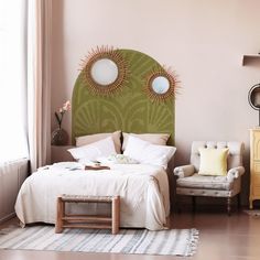 a bedroom with a green headboard and two mirrors on the wall