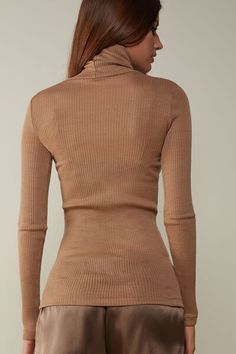 Long-sleeve high-neck tubular top made from a wool-silk blend. Fitted High Neck Beige Sweater, Beige Fitted High Neck Sweater, Elegant High Neck Tops For Winter, Fitted Brown Long Sleeve Turtleneck, Elegant High Neck Winter Tops, Fitted Brown Turtleneck With Long Sleeves, Elegant High Stretch Turtleneck For Fall, Elegant Ribbed Tops For Fall, Elegant High Stretch Turtleneck