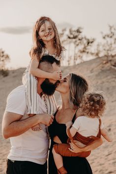 a man, woman and child kissing each other on the beach