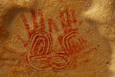 a rock with some writing on it that is red and white in the sand,