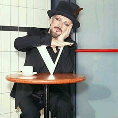 a man in a top hat sitting at a table with a cup and saucer