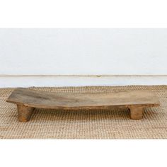 an old wooden bench sitting on top of a rug in front of a white wall