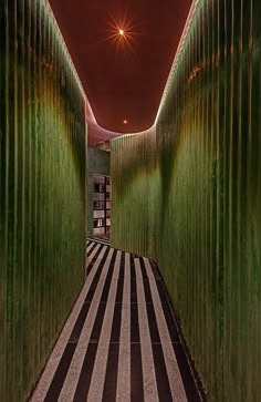 the hallway is lined with green walls and striped flooring, while lights shine brightly in the background