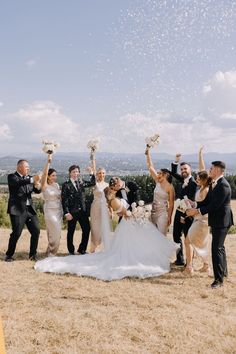 a group of people standing around each other on top of a grass covered field with confetti in the air