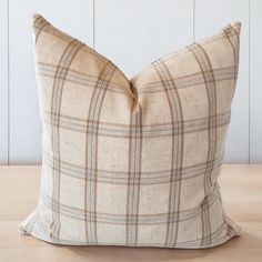 a brown and white plaid pillow sitting on top of a wooden table