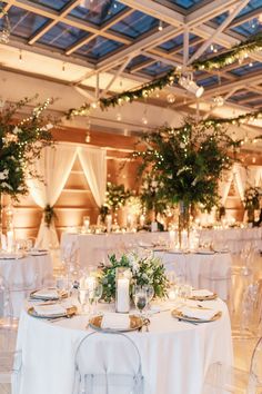 an indoor wedding reception with white linens and greenery