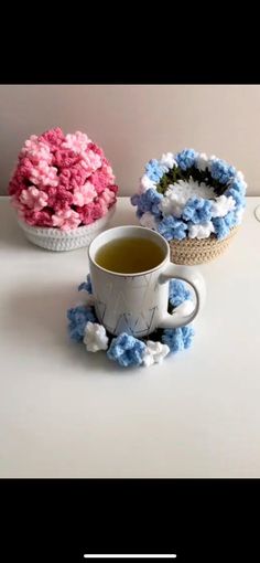 there are three cups with flowers in them on the table, one is filled with tea