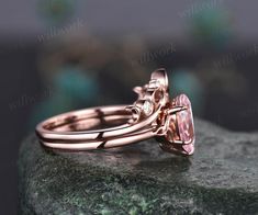 a close up view of a pink diamond ring on top of a rock