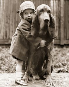 an old photo of a child hugging a dog