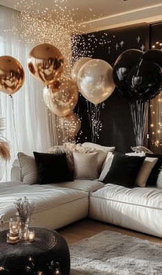 a living room filled with lots of black and white balloons floating over the couches