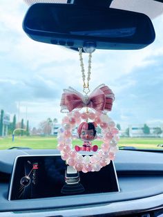 the car dashboard is decorated with pink beads and a doll hanging from it's rearview mirror