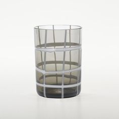 an empty glass sitting on top of a white table next to a black and gray vase