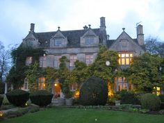 a large house with lots of windows and bushes in front of it at night time