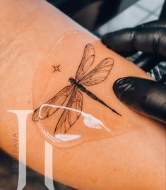 a woman's arm with a dragonfly tattoo on it