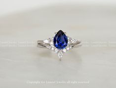 a blue and white diamond ring sitting on top of a table