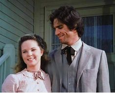 a man standing next to a woman in front of a house