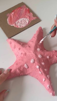 someone is painting a pink starfish on the table