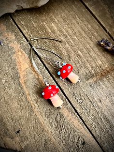 red and white earrings with polka dots on them sitting on a wooden table next to other items