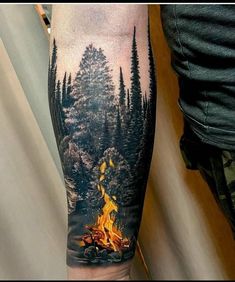 a man's leg with a fire and trees on it