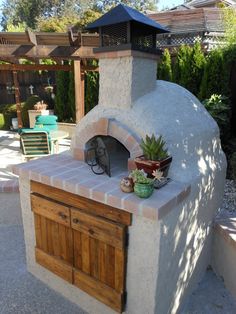 an outdoor pizza oven with potted plants on it