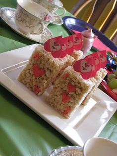 rice krispy treats are arranged on a white plate with red paper hearts attached to them