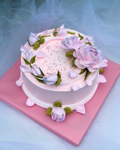 a white cake with pink frosting and flowers on top