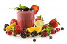 a smoothie with berries, lemons and strawberries on the side