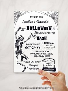 a hand holding up a halloween party card with a skeleton and spider web on it