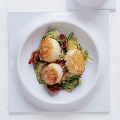 a white plate topped with scallops and vegetables