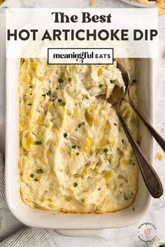 the best hot artichoke dip in a white casserole dish with a spoon