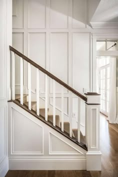 an empty room with wood floors and white walls, along with a wooden banister