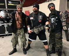 three men standing next to each other holding their wrestling gear