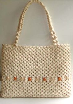 a handbag hanging on the wall in front of a white background with orange beads