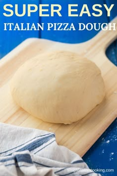 a pizza dough sitting on top of a wooden cutting board next to a blue towel