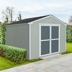 a gray shed sitting on top of a lush green field