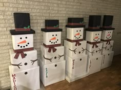 snowmen made out of paper bags sitting in front of a brick wall