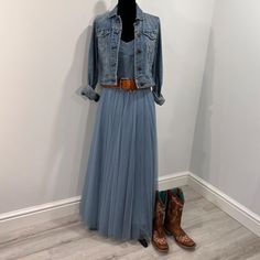 a woman's dress and cowboy boots are on display in a room with white walls